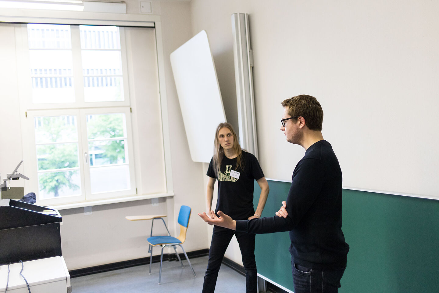 Zwei Referierende vor einer Tafel diskutieren.